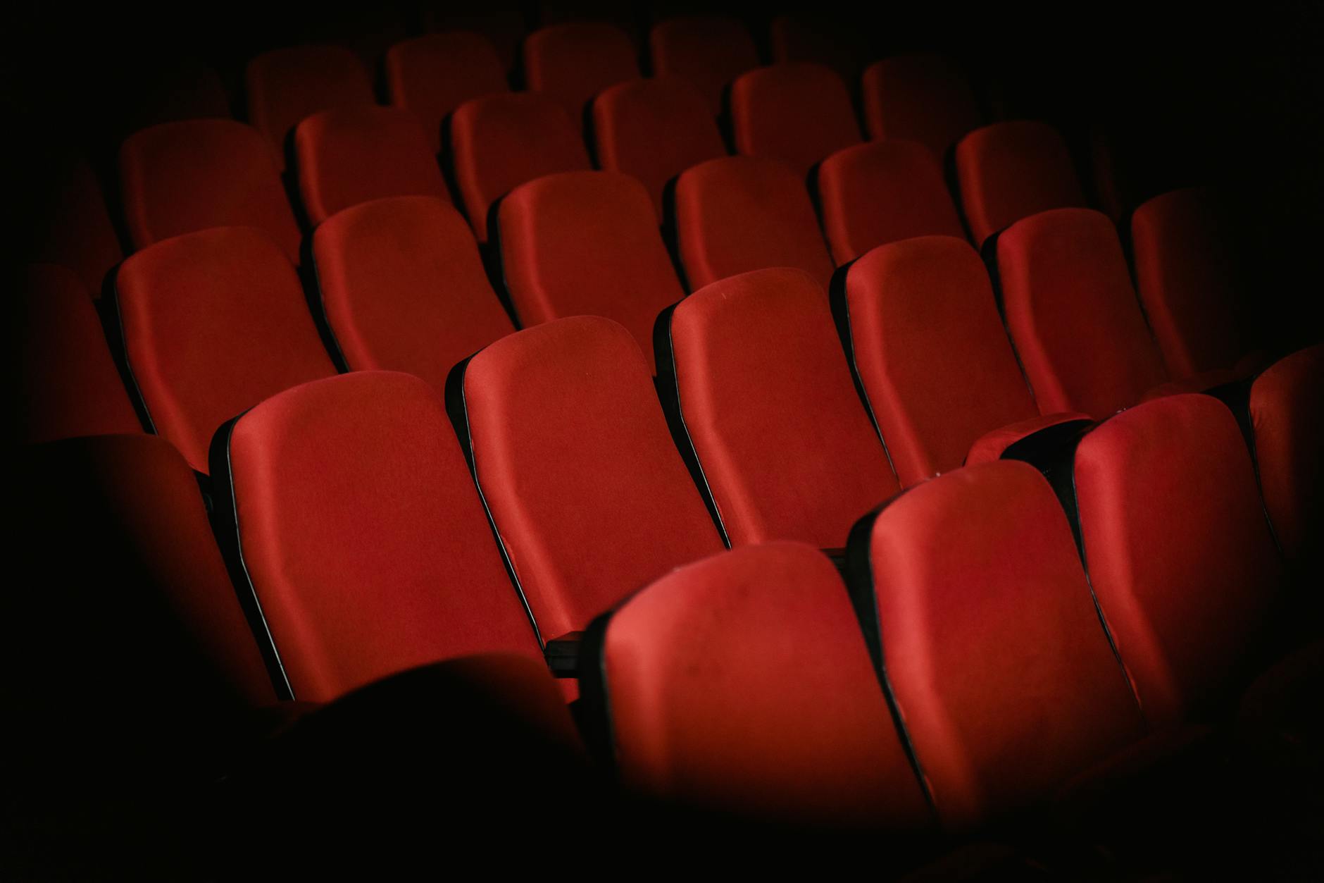 Empty movie theater auditorium with red seats and large screen