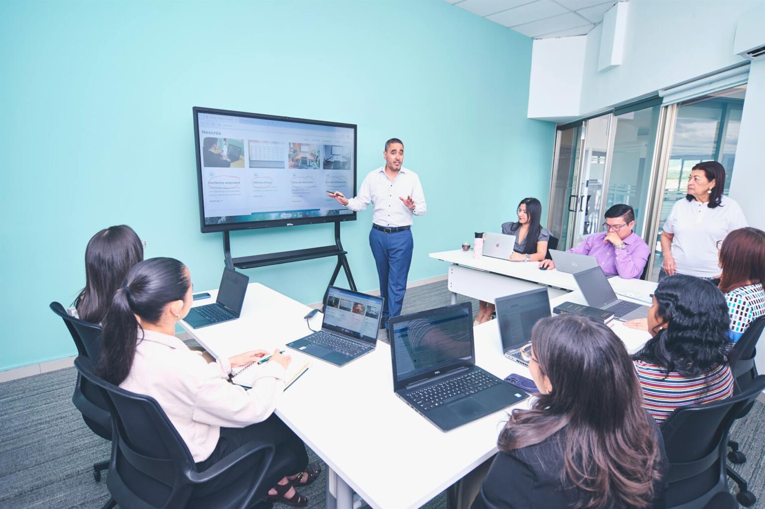 Business professionals in modern office training environment with laptops and presentation screens
