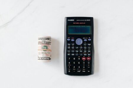 Calculator and education savings documents on desk showing financial planning for educational expenses