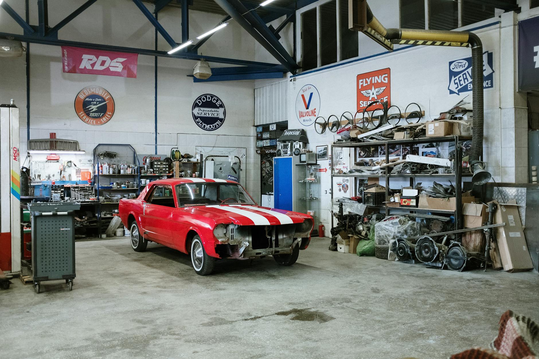 Mechanic working under the hood of a car in an automotive repair shop