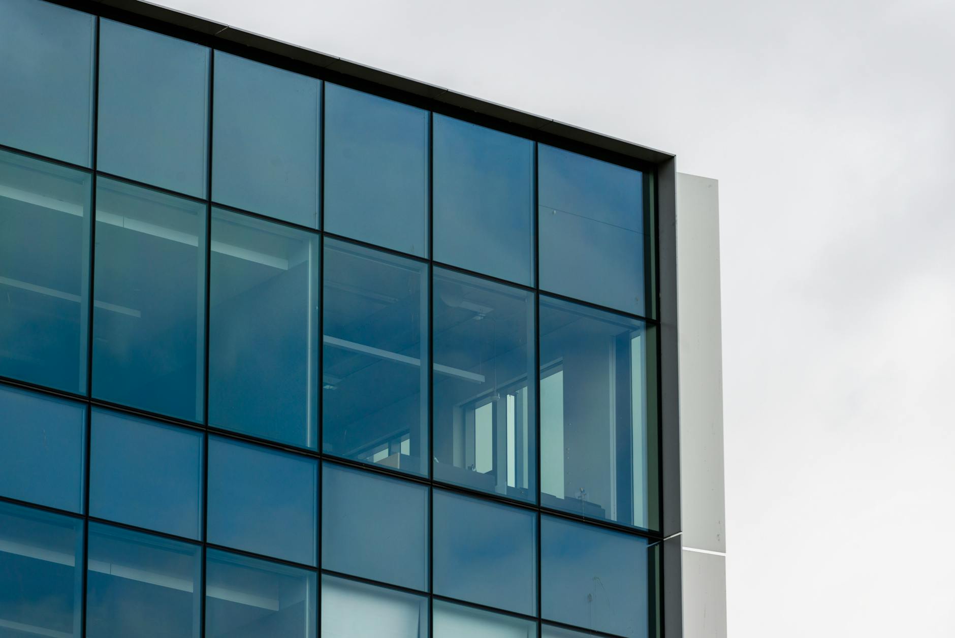 Modern office building exterior with glass windows reflecting urban skyline