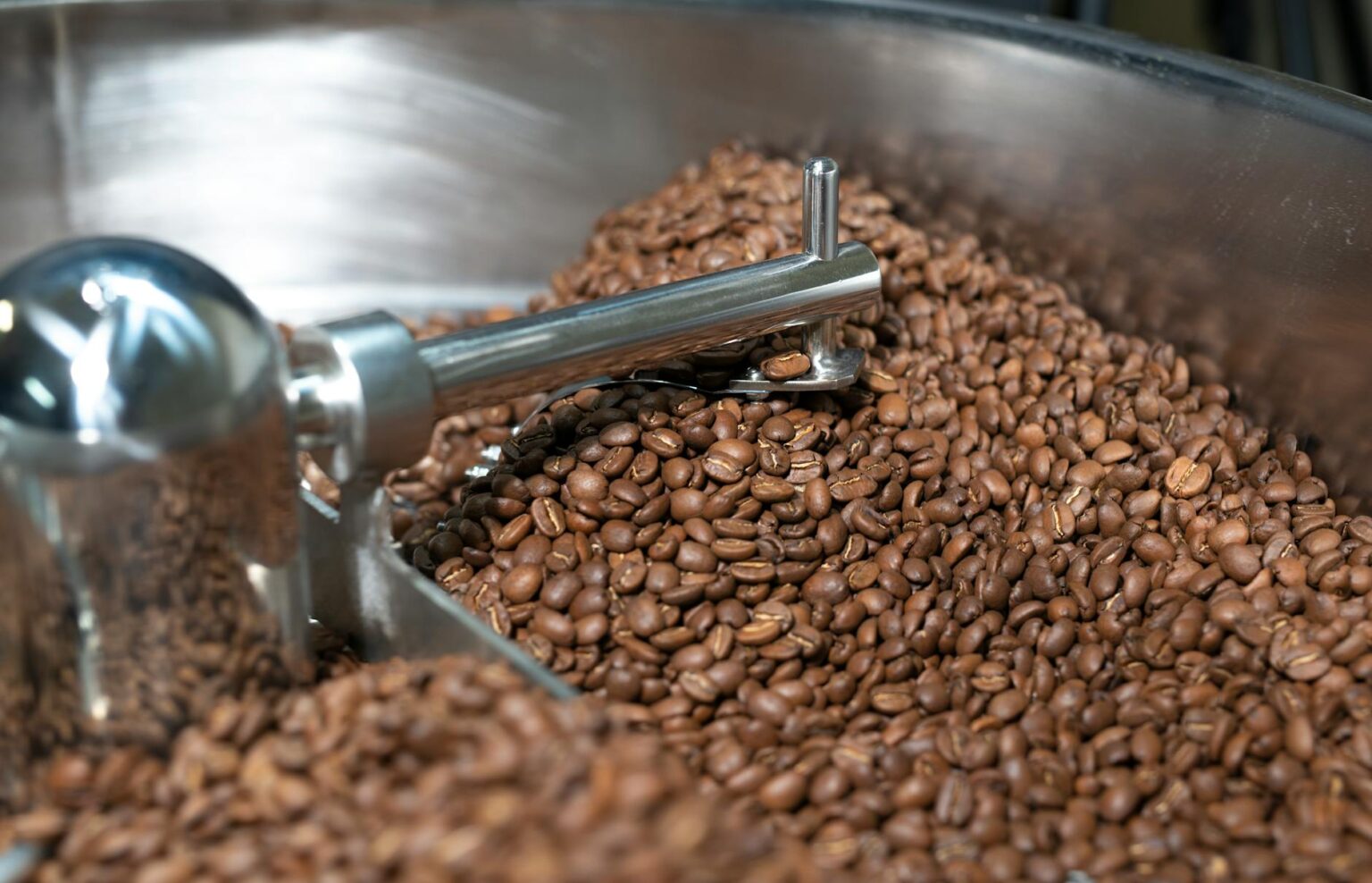 Coffee beans being roasted in industrial roasting machine at independent coffee roastery
