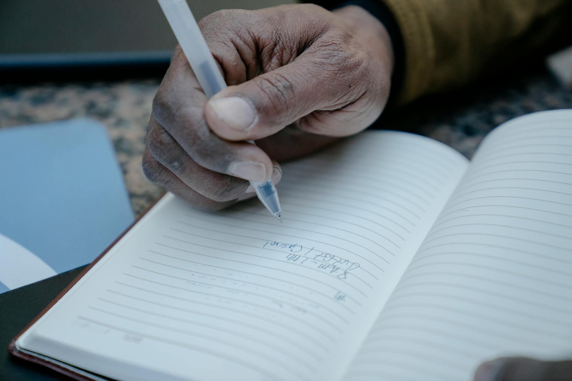 Person writing in notebook with pen during analog work session