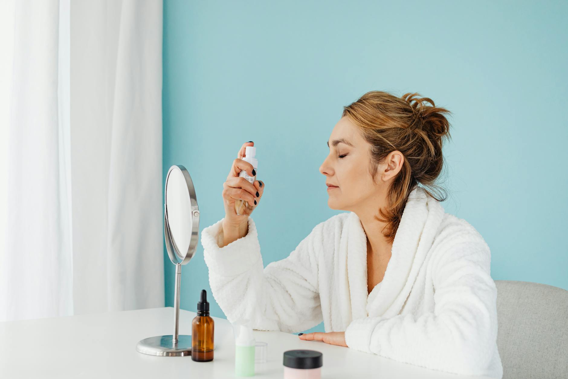 Woman applying skincare product while looking in bathroom mirror