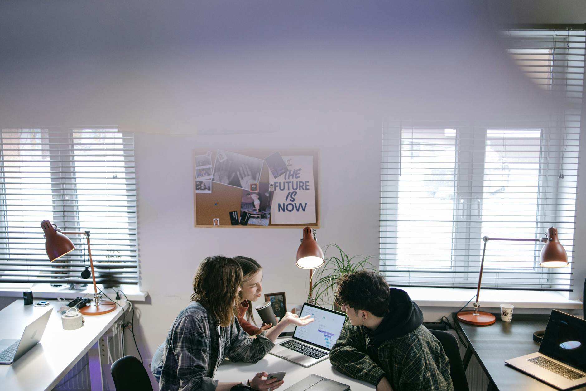 Diverse team of employees working together on laptops and documents in an open office environment