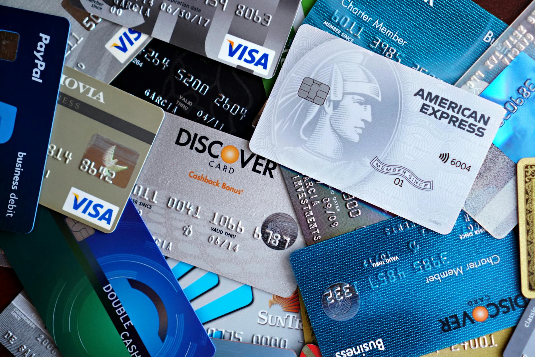 Multiple credit cards spread on desk next to laptop computer