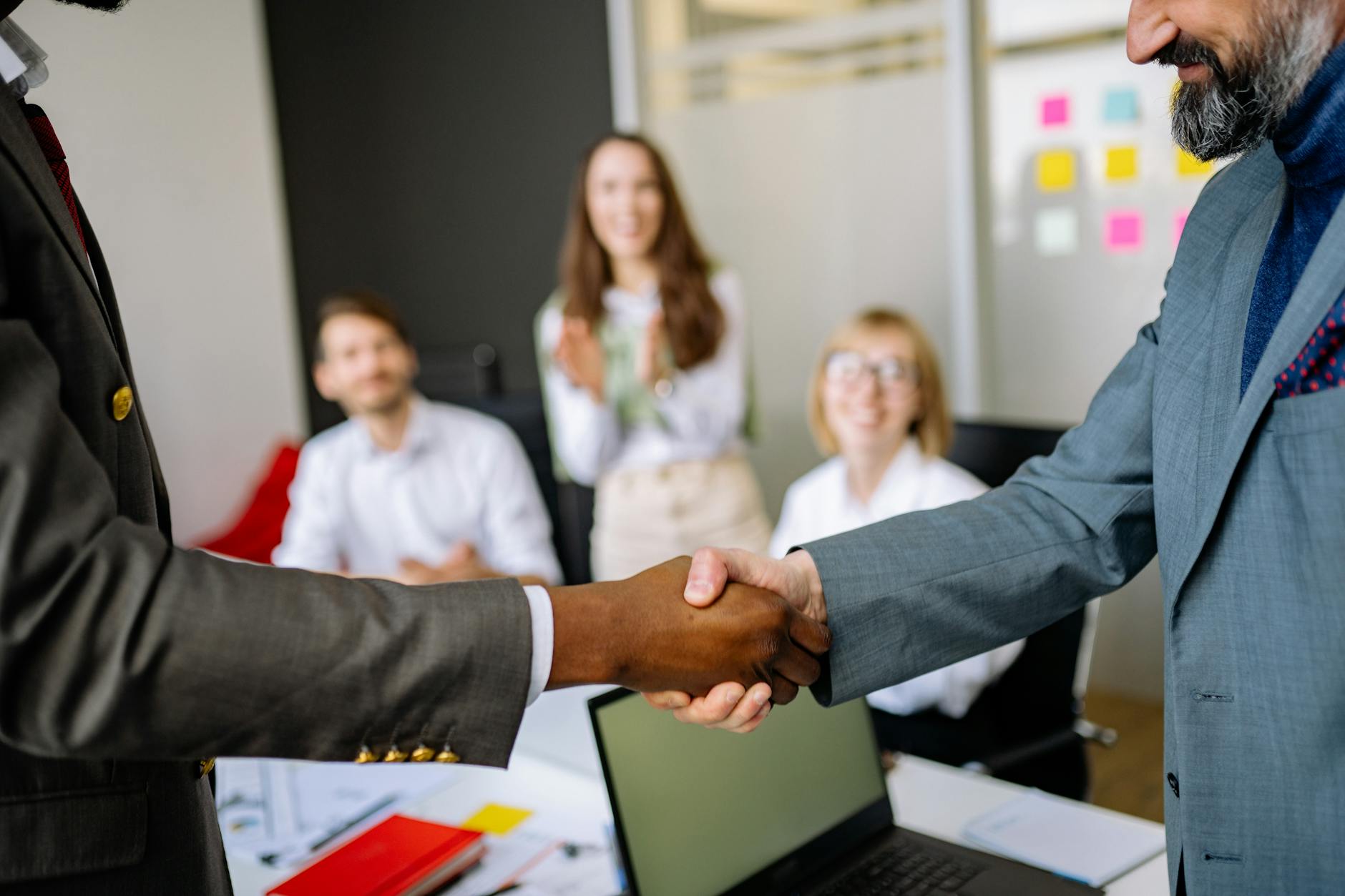 Business professionals shaking hands over partnership agreement in modern office setting
