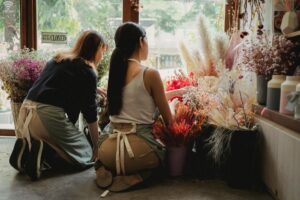 Person's hands working on flower arrangement during educational workshop class