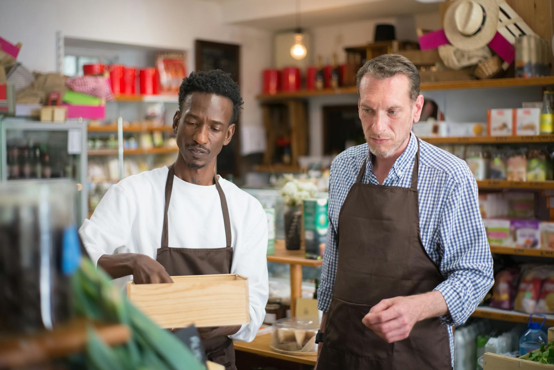 Hardware store owner standing behind counter with rental equipment visible in background