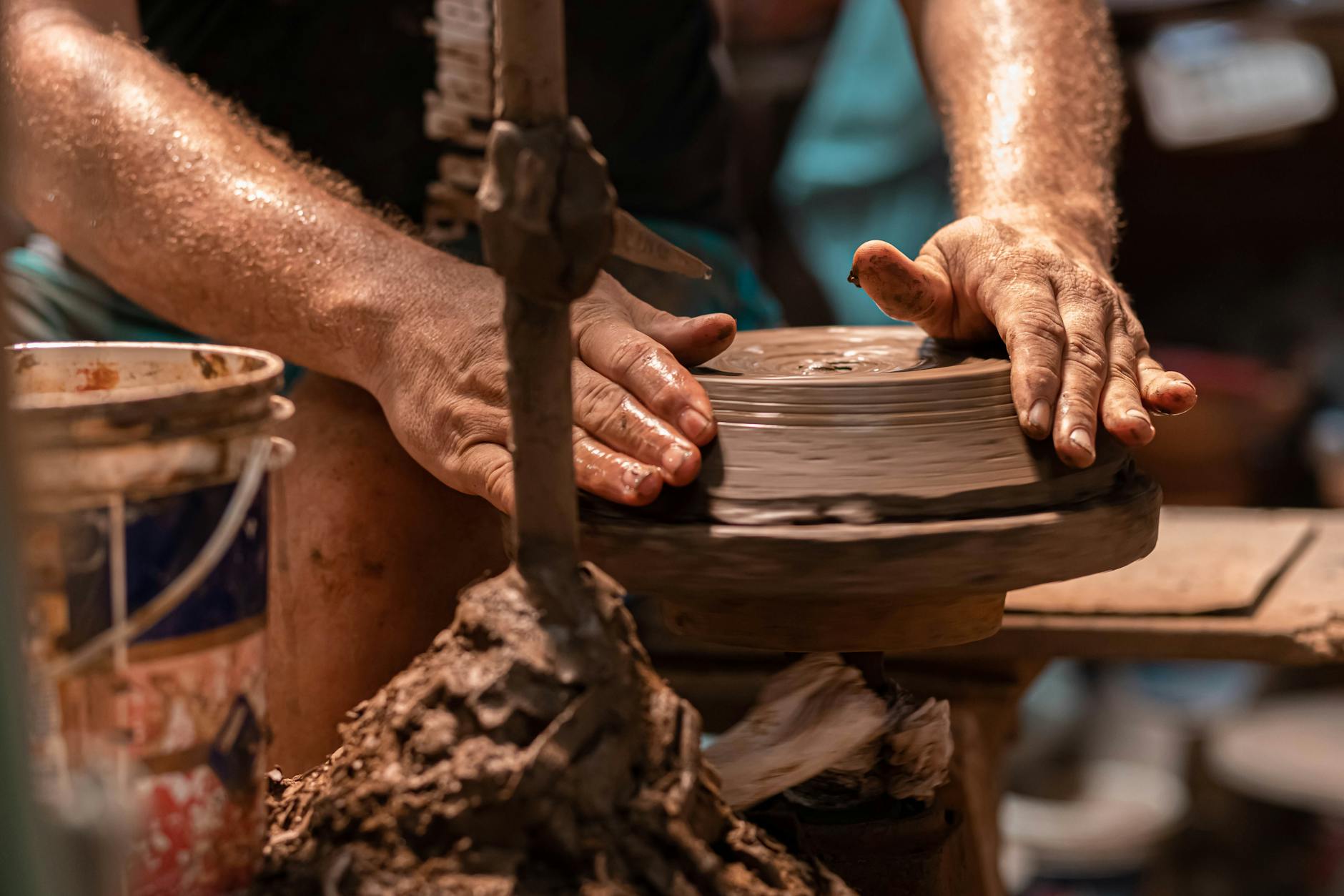 Hands shaping clay on a pottery wheel during a group session