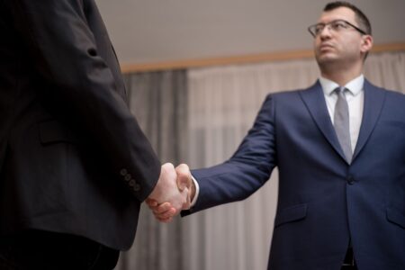 Leveraged Buyout Activity Quietly Rebounds as Credit Spreads Tighten Two professionals shaking hands at a business meeting, representing a private equity acquisition deal