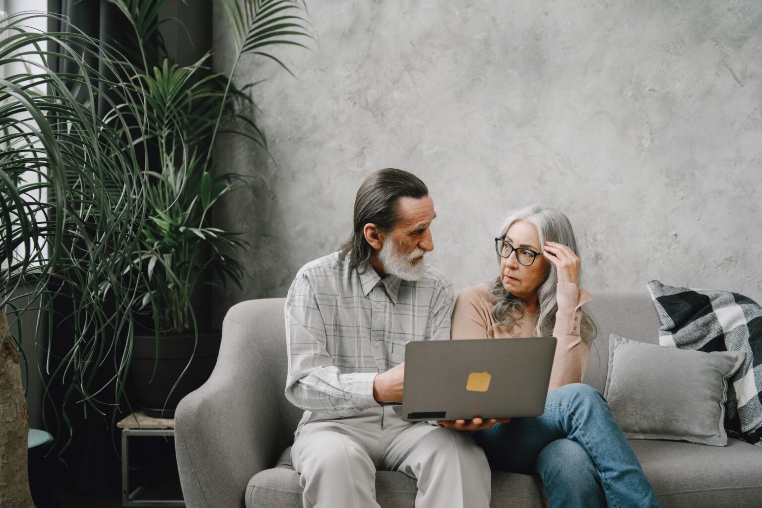 A retired couple reviewing financial documents at a home office desk