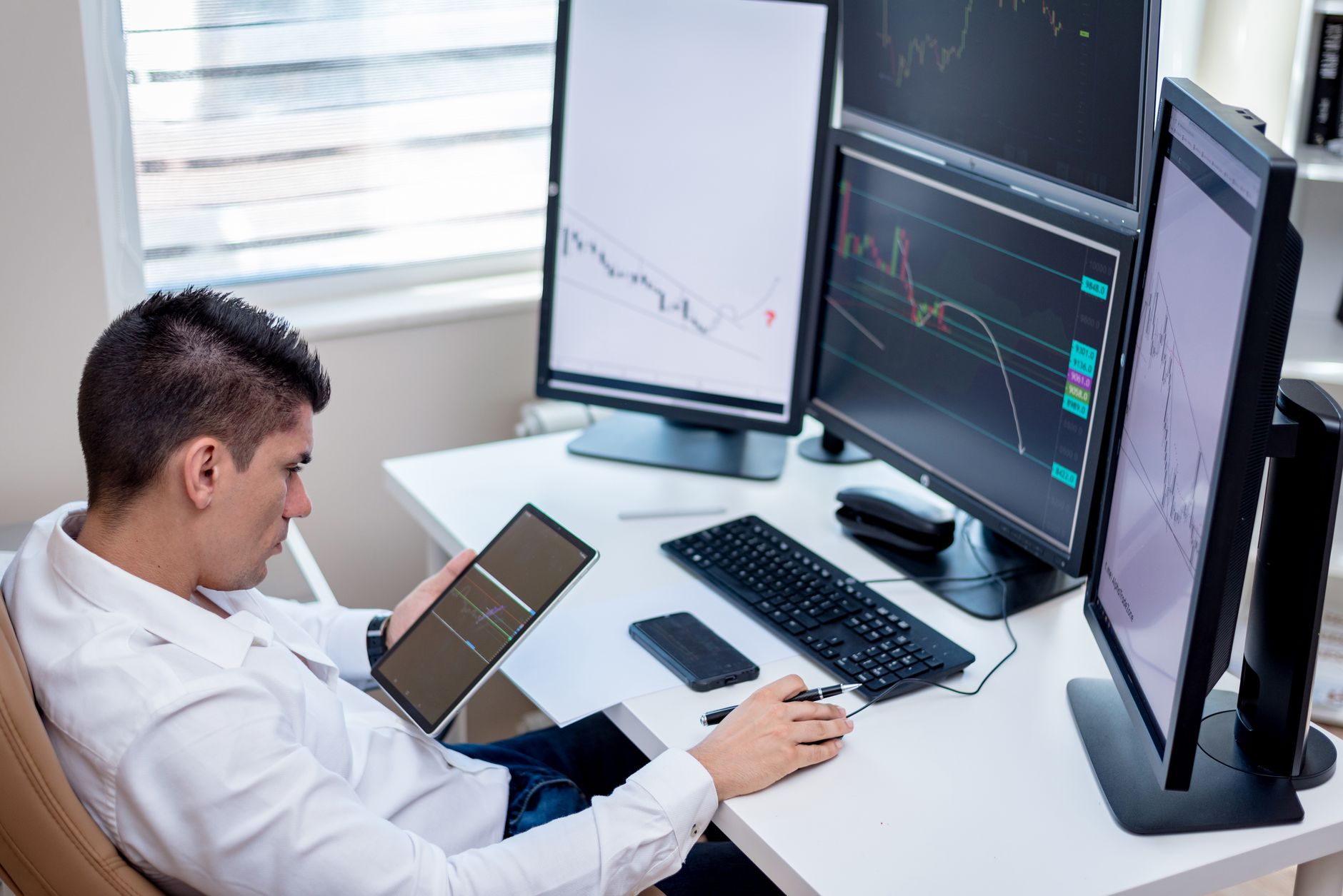 Trader monitoring multiple financial screens in a professional trading office