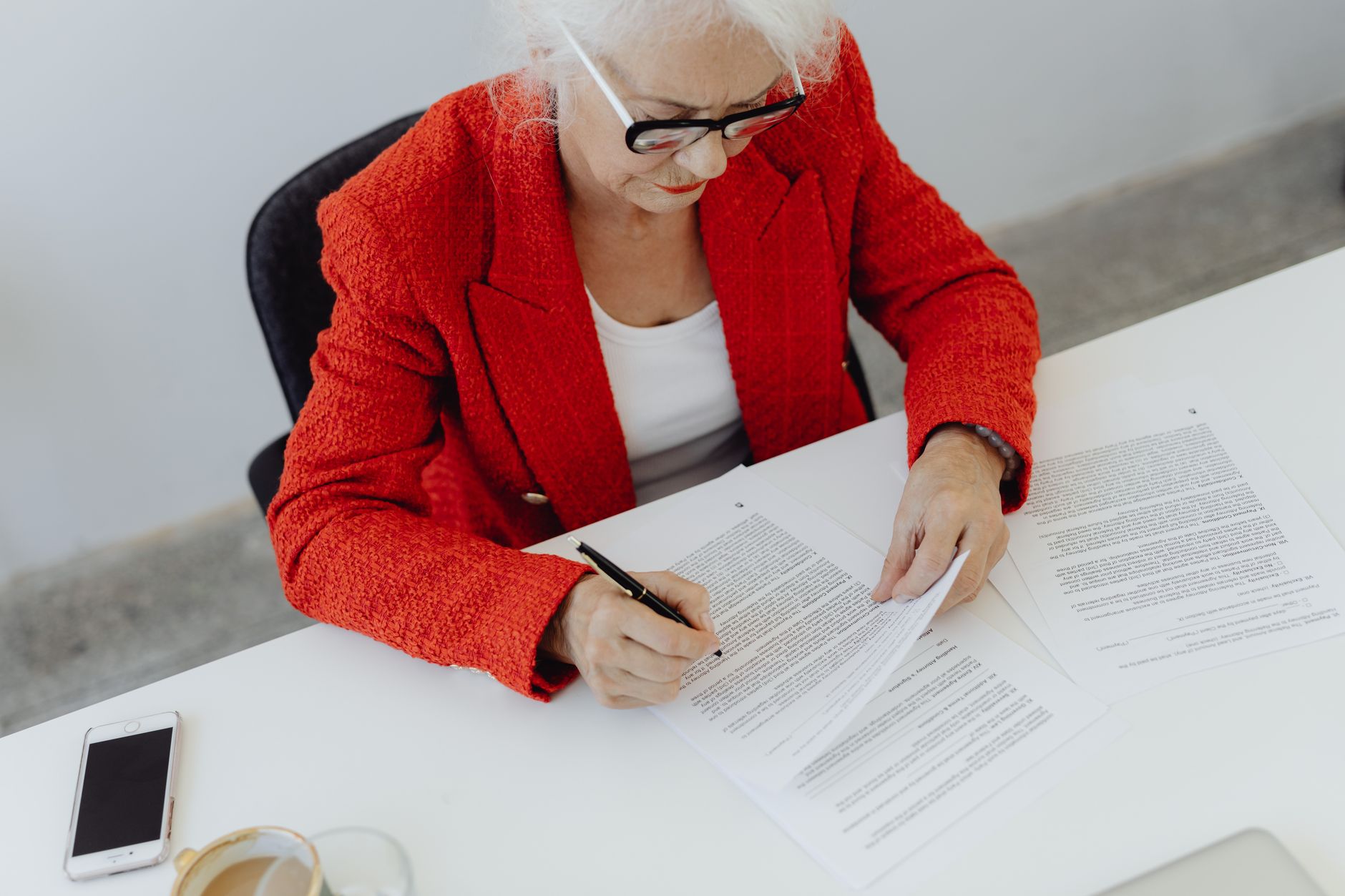 An older adult reviewing and signing financial contract paperwork