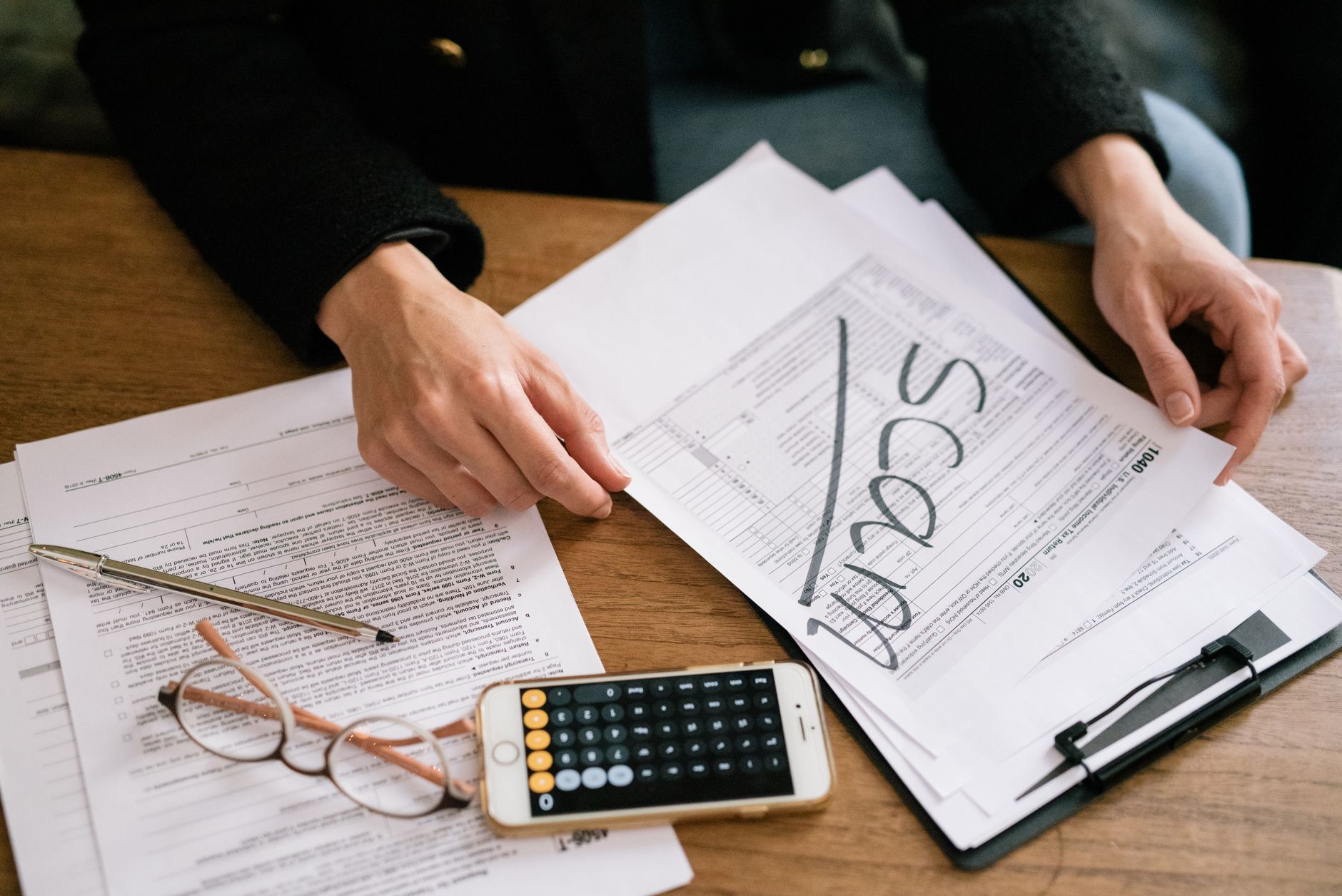 Tax documents and financial paperwork spread across a desk representing after-tax investment calculations