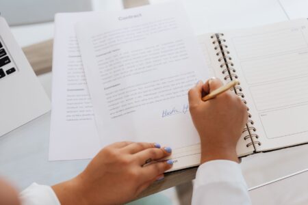 Royalty Streaming Contracts Quietly Attract Yield-Hungry Private Allocators Two professionals signing a financial contract at a desk, representing royalty streaming agreements