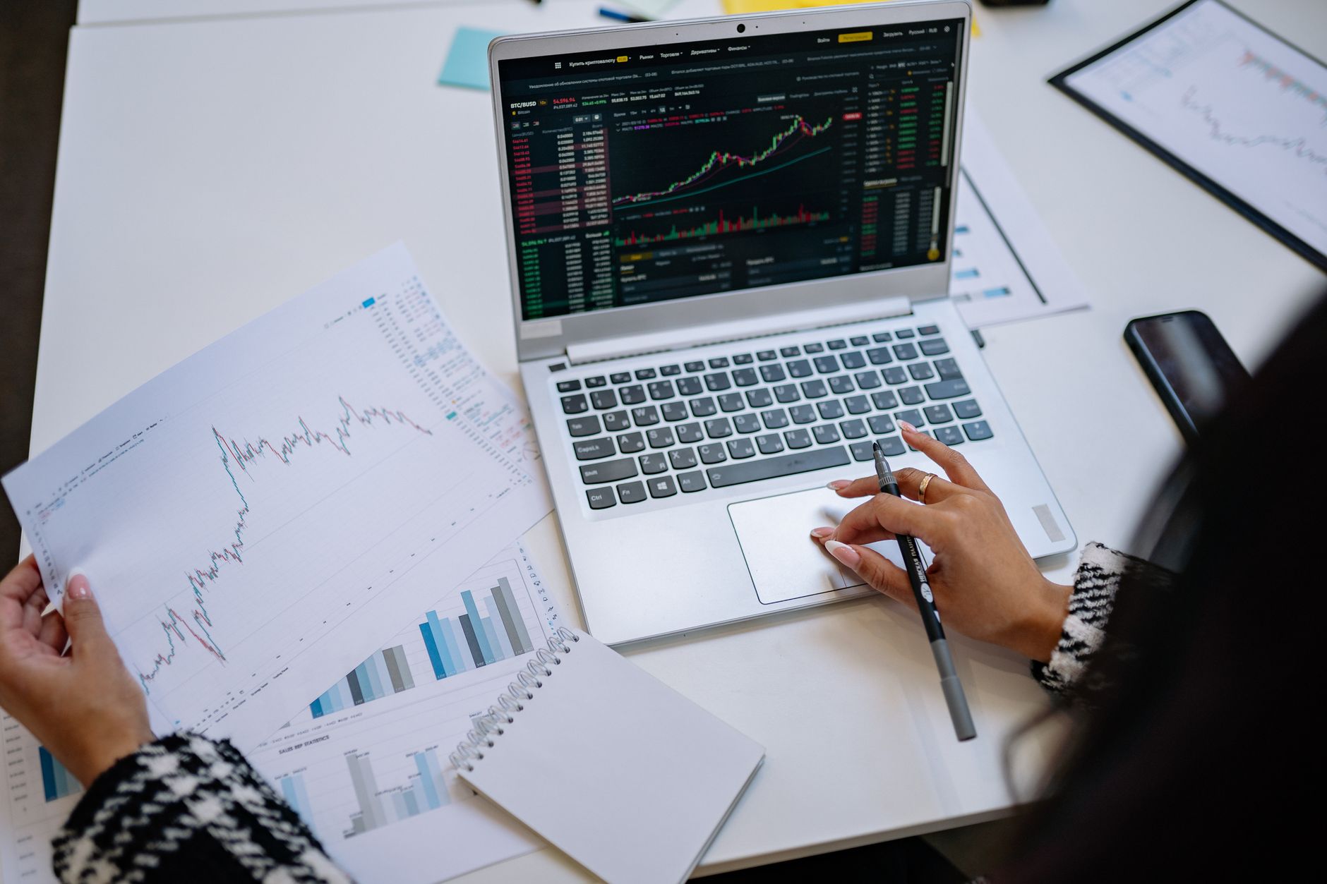 Investment analyst reviewing market charts on multiple screens in an office setting