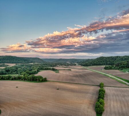 Farmland REITs Quietly Attract Inflation-Hedging Institutional Capital Aerial view of rows of crops on flat agricultural farmland