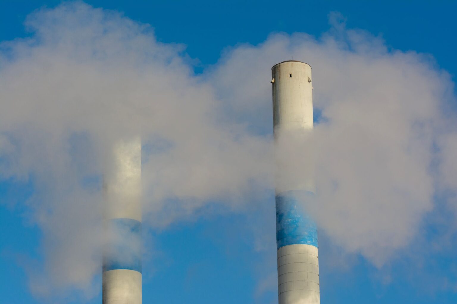Carbon Credit Forward Contracts Quietly Attract Compliance-Driven Institutional Buyers Industrial facility emitting smoke, representing carbon emissions compliance pressures on manufacturers