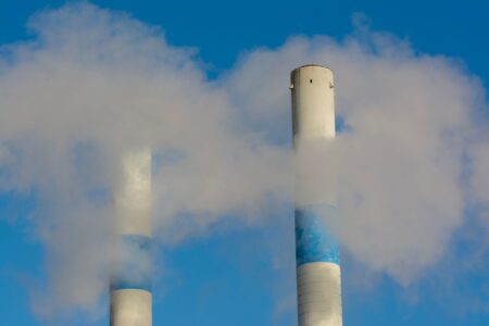 Carbon Credit Forward Contracts Quietly Attract Compliance-Driven Institutional Buyers Industrial facility emitting smoke, representing carbon emissions compliance pressures on manufacturers